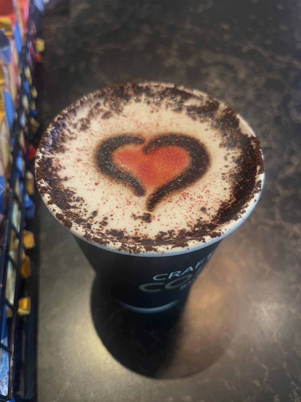 A cappuccino with a red heart drawn in thick chocolate dusting